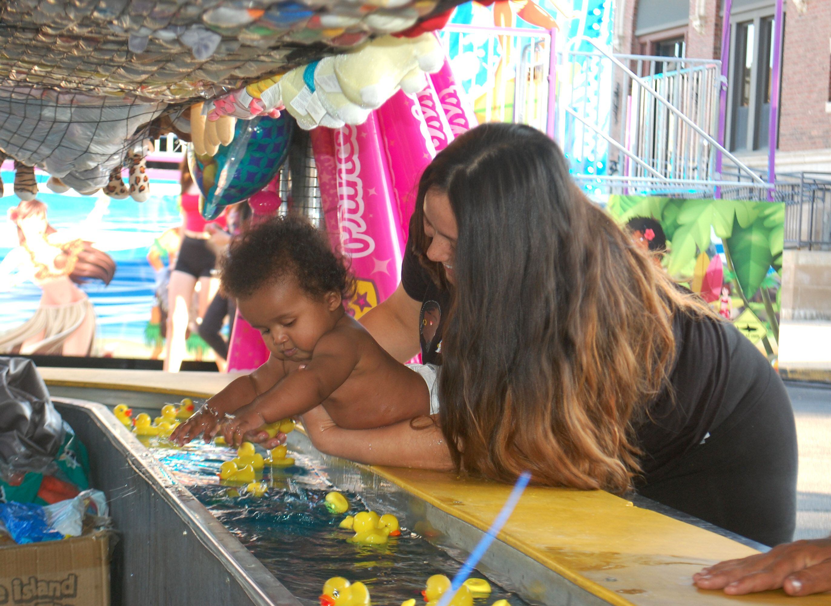 A toddler splashes in the water while trying to catch a rubber duck during a carnival game Friday, May 26, 2023, at Park Fest in downtown Streator.