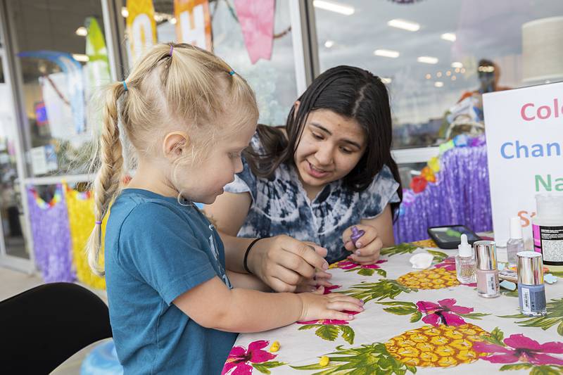 Danielle Cantu sparkles up Stella Nagy’s fingernails Saturday, June 8, 2024, at the Summer Block Party in Dixon. Kids could play games and make crafts while visiting various service booths.