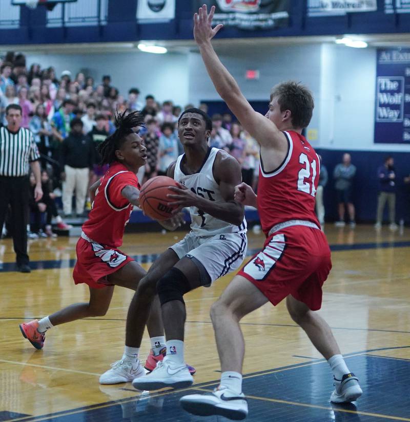 Oswego East's Andrew Wiggins (1) plays the ball in the post against Yorkville's Michael Dunn (left) and Taelor Clements (21) during a basketball game at Oswego East High School on Friday, Dec 8, 2023.