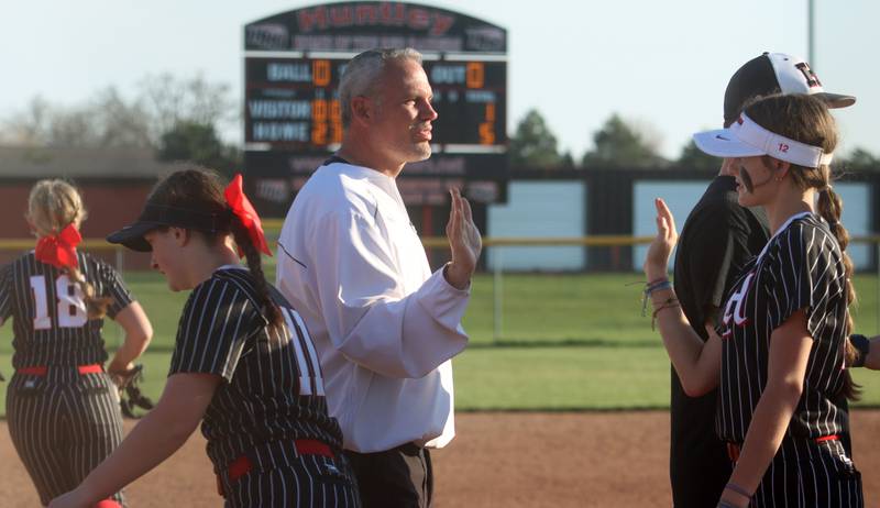 Huntley’s head coach Mark Petryniec congratulates his Red Raiders after a win over McHenry in varsity softball at Huntley Friday.