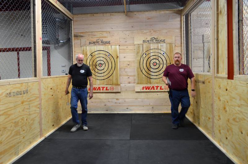 Rustic Ridge Axe Throwing manager Chris Chapman, right, and ax-throwing coach Mike Luse gather the axes they threw as part of a short competition they held during the business' grand opening on May 28. Rustic Ridge Axe Throwing is located at 117 N. 4th St., Oregon, and is affiliated with the World Axe Throwing League.