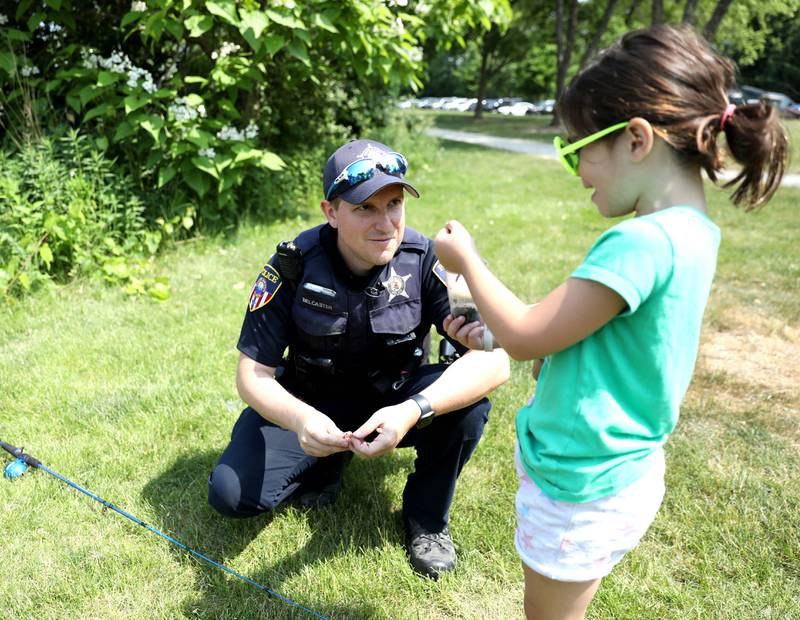 Wheaton Police Officer Ben Belcaster helps Meredith Rose, 6, of Wheaton with her worms during the Wheaton Police Department and DuPage County Forest Preserve Police Cops & Bobbers community fishing event at Herrick Lake Forest Preserve in Wheaton on Wednesday, June 7, 2023.