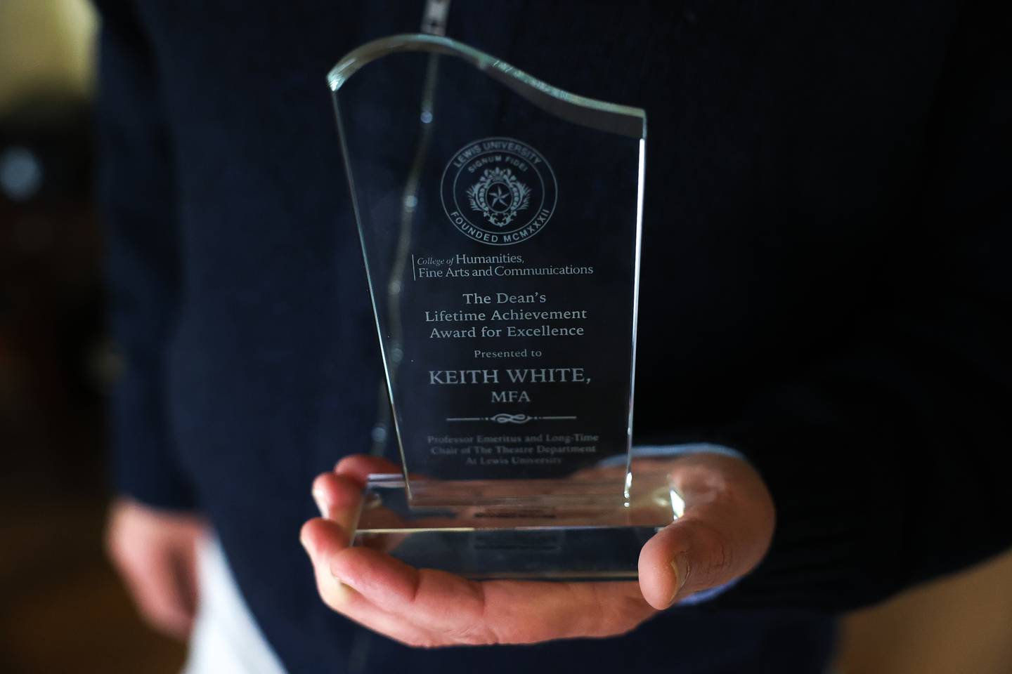 Retired theater director Keith White holds his Dean’s Lifetime Achievement Award for Excellence the first-ever presented by Lewis University on Thursday, April 11, in Joliet.