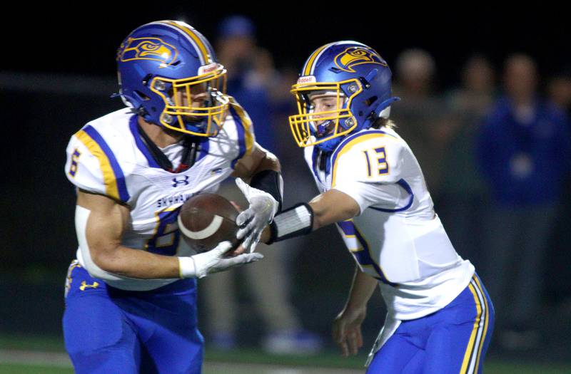 Johnsburg’s Carter Block, right, hands the ball off to Brett Centnarowicz in varsity football action on Friday, Sept. 13, 2024, at Richmond-Burton High School in Richmond.