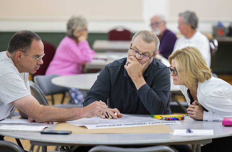 Eric Brown (left), with Greg and Heather Huffman, sketch out their ideas for housing improvements in Dixon Wednesday, Aug. 21, 2024. The city hosted a visioning meeting at the Loveland Building to gather information from the public on future city planning.