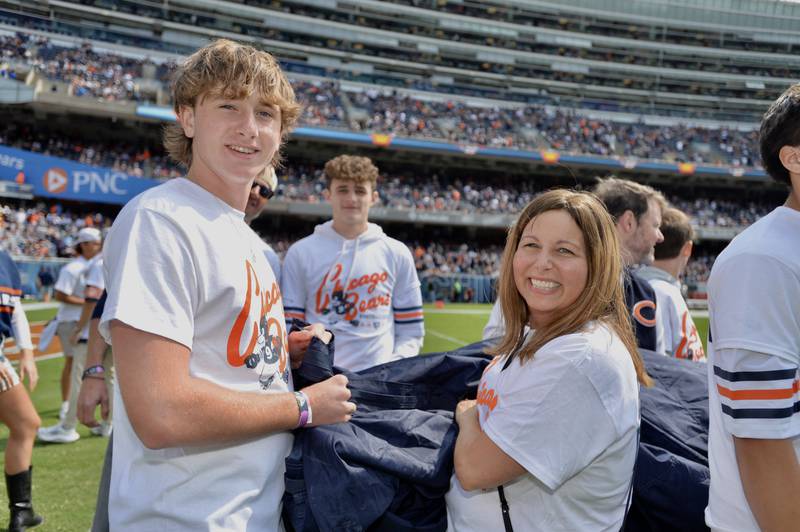 Julie Hermann, right, and her son Jack Hermann unfold the "Bear Down" flag during the Chicago Bears opening game at Soldier Field.