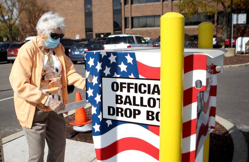 Elaine Manchen of Villa Park deposits her mail-in ballot into a ballot box on the campus of the DuPage County administration headquarters in Wheaton.