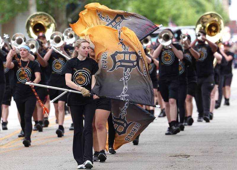 The DeKalb High School flag team and marching band walk down West Locust Street during the DeKalb Memorial Day parade Monday, May 27, 2024, on their way to the parade termination at Ellwood House where a Memorial Day ceremony wraps up the events.