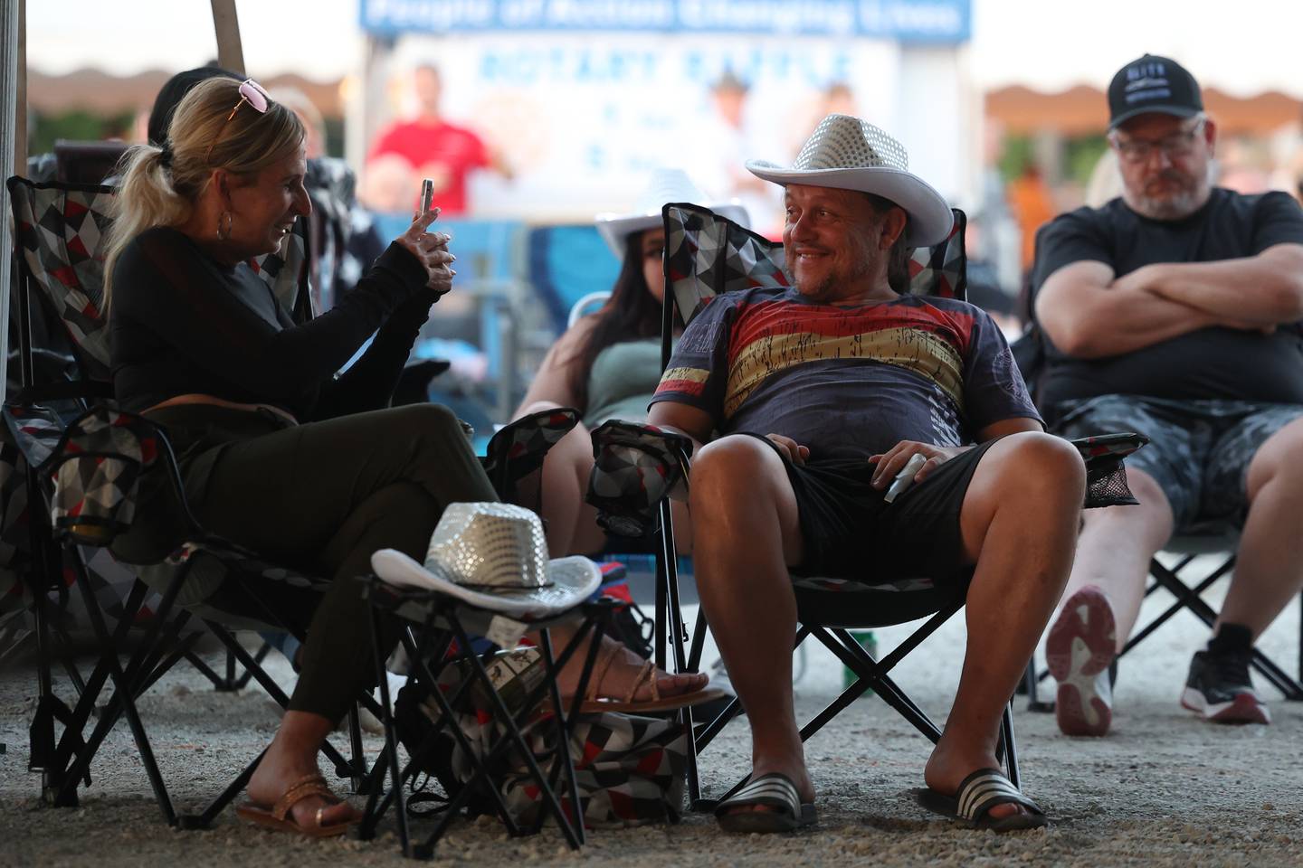 Krissy Norkaitis, left, takes a photo of Linas Jakovlevas wearing a novelty cowboy hat while listening to live music at the Beer Garden tent at Lockport’s Canal Days on Friday, June 9, 2023.