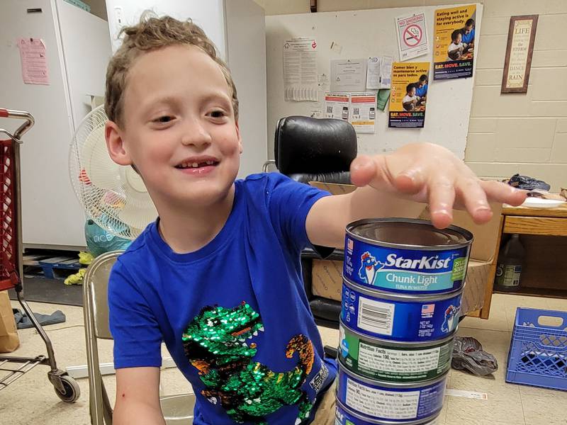 Six-year-old Maximilian Claahsen stacks some of the cans of tuna donated to the Marseilles Food Pantry in honor of his upcoming birthday. His drive netted 1,144 cans for those in need.