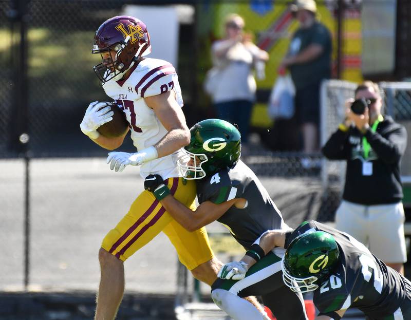 Loyola's Brendan Loftus sheds Glenbard West tacklers Mason Ellens (4) and Danny Campanella (20) on his way to a touchdown during a game on September 7, 2024 at Glenbard West High School in Glen Ellyn.