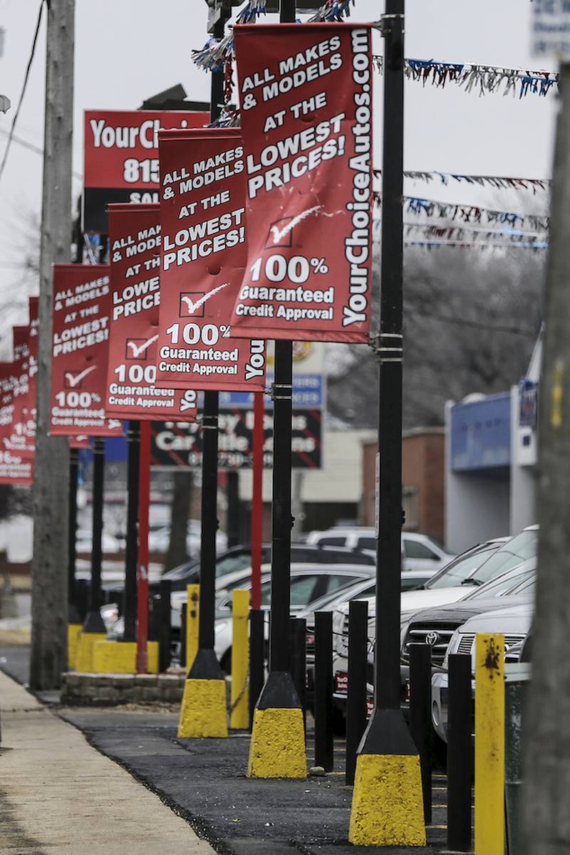 Signs hang from the light post at a car dealership on Jefferson Street near the intersection of Stryker Avenue in Joliet on Thursday.