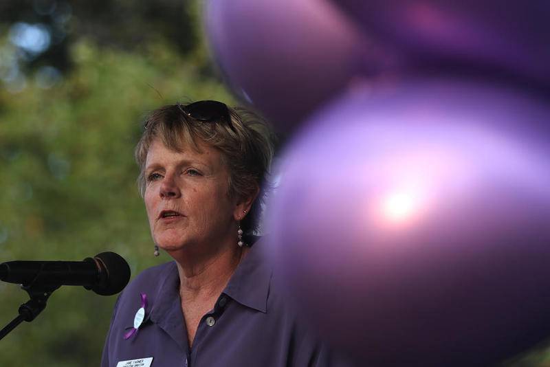 Jane Farmer, executive director of Turning Point, speaks Oct. 3, 2018, at the podium surrounded by purple balloons during a candlelight vigil put on by Turning Point, Mather's Clinic and the Child's Advocacy Center to raise awareness for the problem of domestic violence at the historic Woodstock Square in Woodstock.