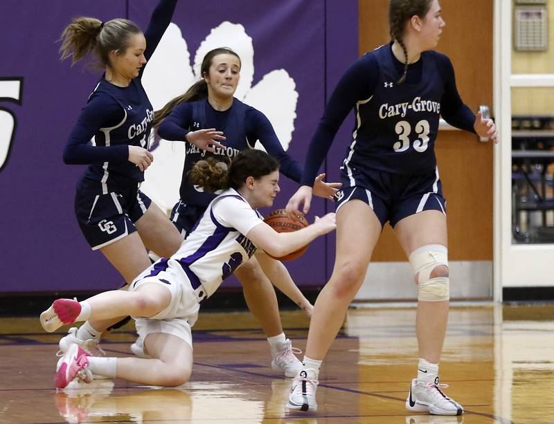 Hampshire's Ashley Herzing falls as she tries to go through the Cary-Grove defense of Kayli McMorris, Sam Skerl, and Ellie Mjaanes during a Fox Valley Conference girls basketball game Friday, Jan. 26, 2024, at Hampshire High School.