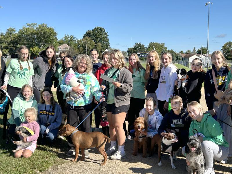 Polo Student Council member Alayna Young presents a $500 donation to Michelle Longtin of Happy Tails Humane Society following the 2024 Doggy Dash on Saturday, Sept. 7, 2024. The event also included a costume contest.