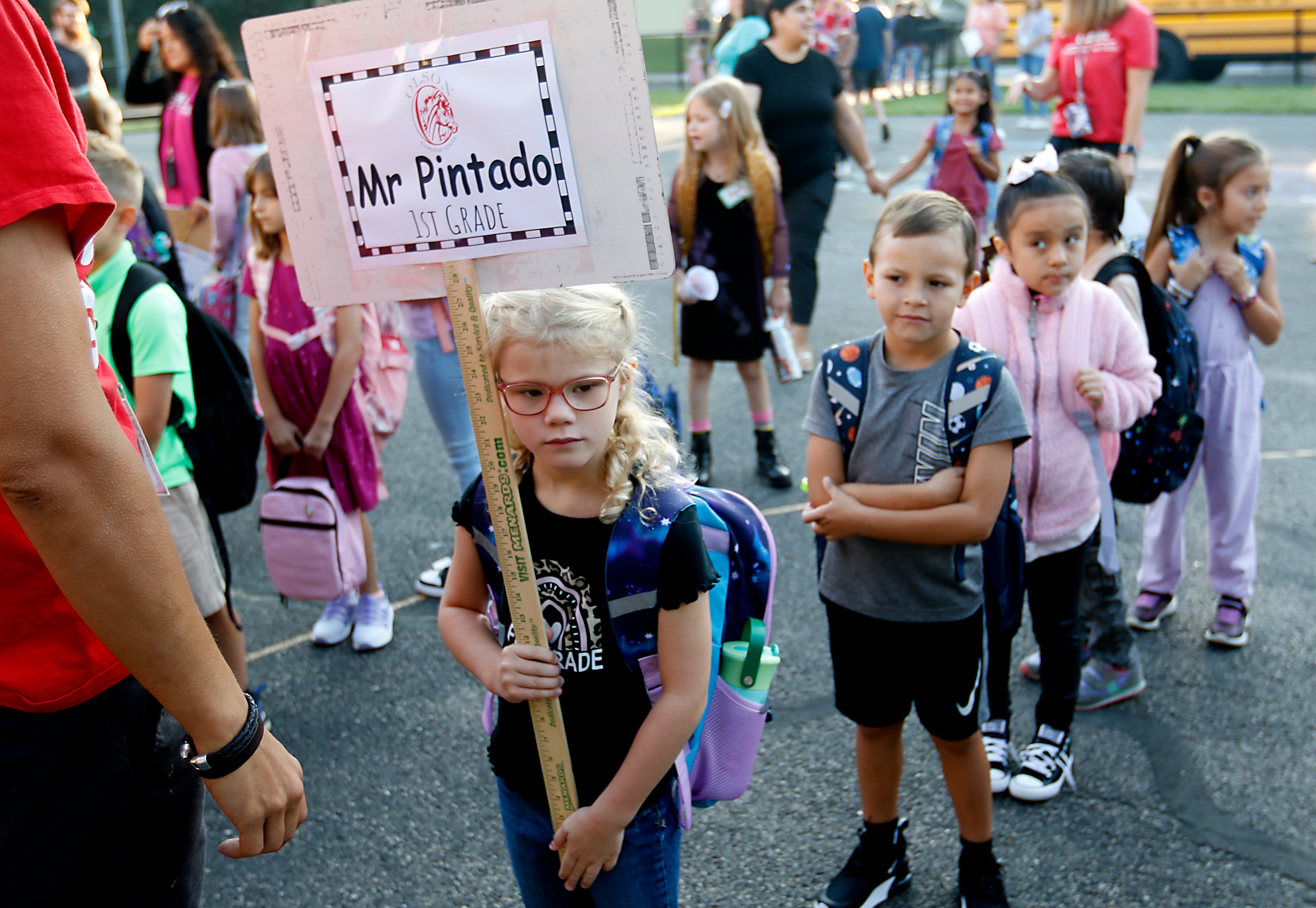 Olivia Goode holds the classroom sign as other students line up behind her for the first day of school at Olson Elementary School in Woodstock, on Wednesday, Aug. 14, 2024.