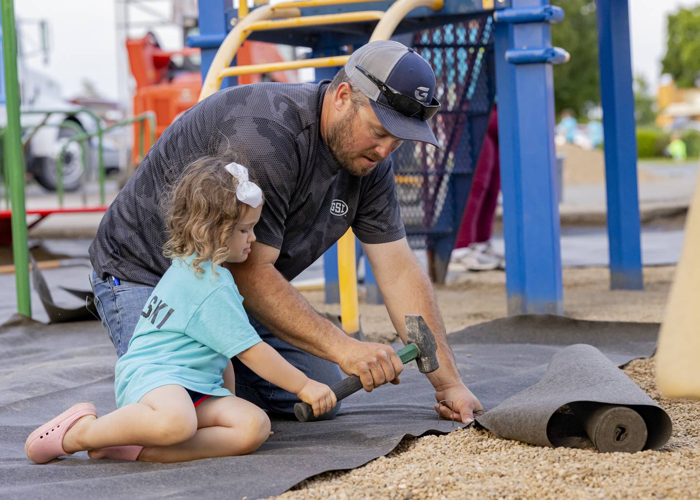 Brooke Kowalski helps her dad Kyle hammer staples into landscaping fabric at Tonica Grade School on June 3, 2024.