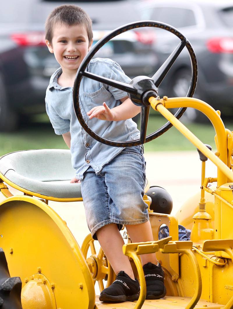 Milo Williams, 5, of Cortland, smiles as he gets on one of the tractors on display Saturday, July 16, 2022, at the Waterman Lions Summerfest and Antique Tractor and Truck Show at Waterman Lions Club Park.