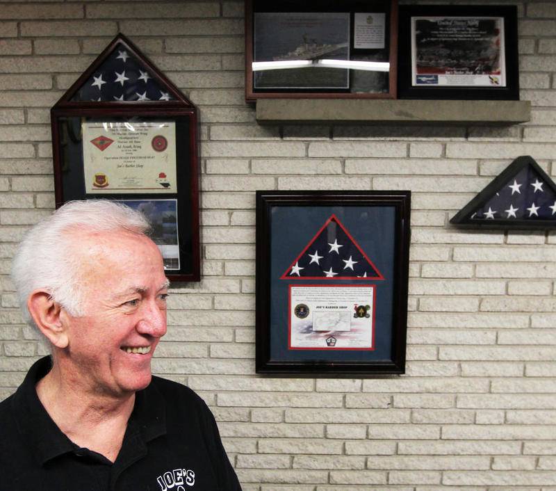 Jack McArdle of Joe's Barber Shop in Crystal Lake, shown in a 2020 photo, honors veterans by displaying flags, military artwork, caps and more. Many of the items have been donated by customers.