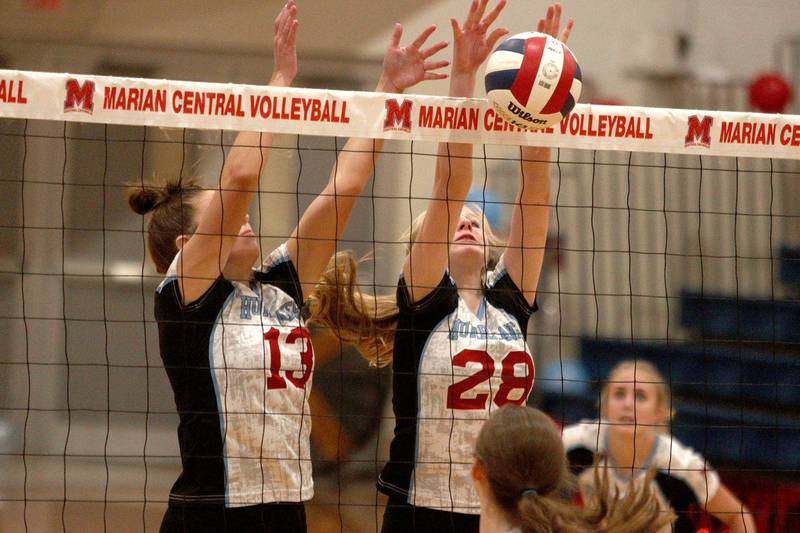 Marian Central’s Lucy Iden (13) and Nola Midday (28) block against Grayslake North in girls volleyball in Woodstock Monday.