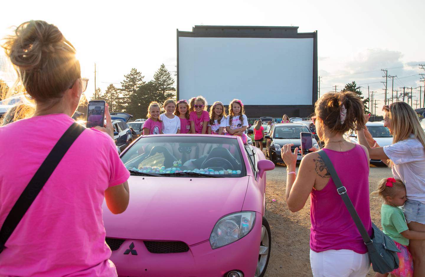 Girls pose for a photo in a car owned by Lacy of Ingleside before the "Barbie" movie premiere at the McHenry Outdoor Theater on Friday,  July 21, 2023.  Lacy painted the car to look like the car that Barbie drives.