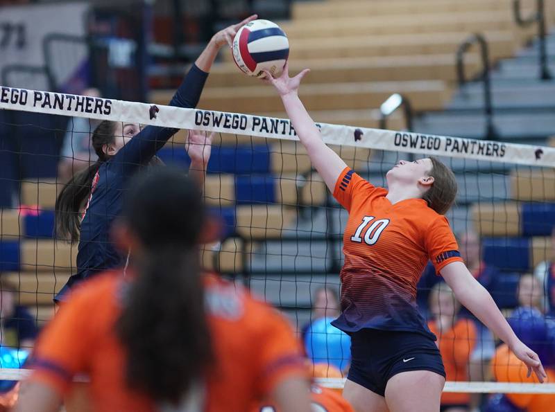 Oswego’s Sidney Hamaker (13) and Romeoville's Kameron Blizniak (10) play the ball above the net during a volleyball game at Oswego High School on Tuesday, Oct. 17, 2023.