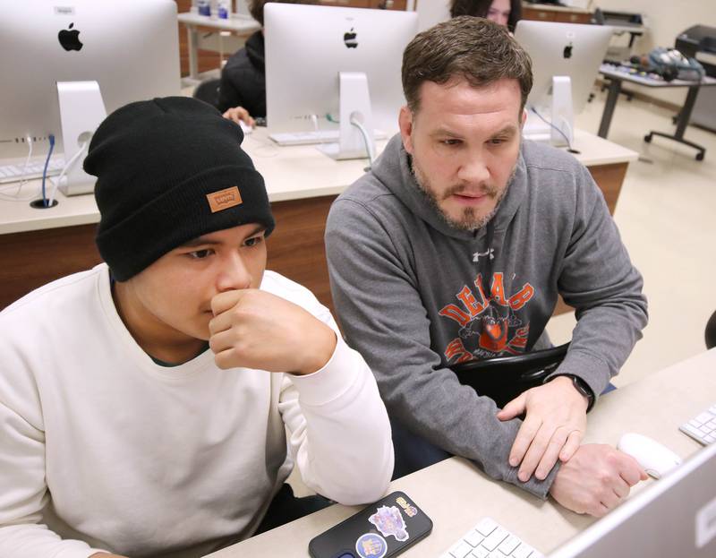 JD Oliva, (right) faculty advisor for BarbCast, helps a student during class Thursday, March 7, 2024, at DeKalb High School. Oliva works with students who are part of the BarbCast network that broadcasts live streaming video of sports and events at the school as well as putting together promotional materials.