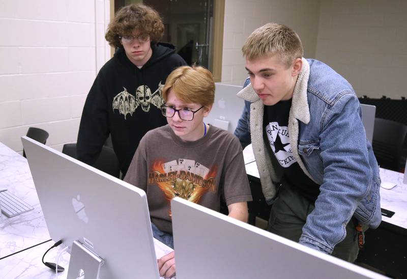 Johnny Howard, (left) a junior, Owen Foster, a junior, and Lane Schumacher, (right) a senior, at one of the computers Thursday, March 7, 2024, at DeKalb High School. The students are part of the BarbCast network that broadcasts live streaming video of sports and events at the school as well as putting together promotional materials.