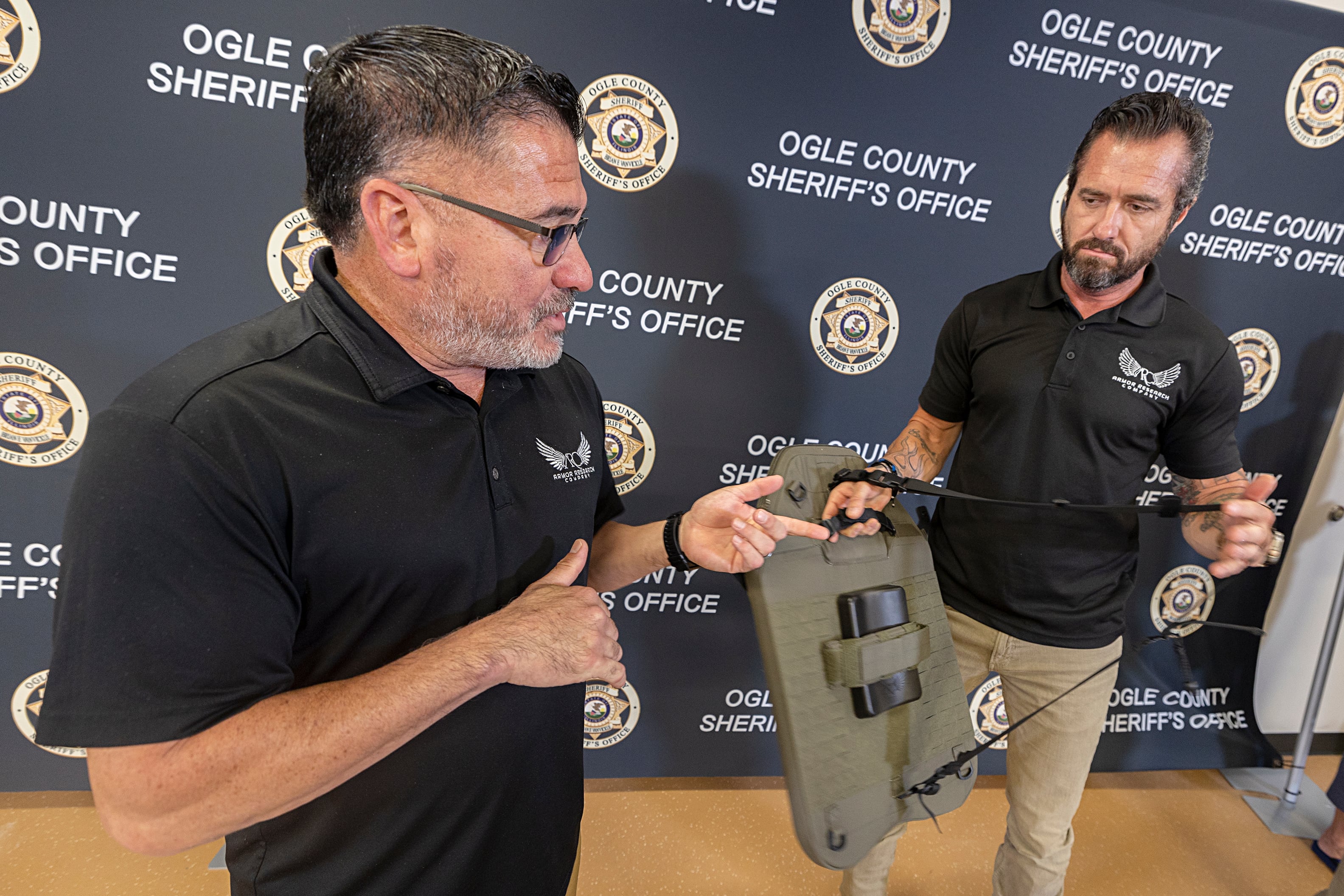 Armor Research Company representatives George Chavez (left) and Jim Nunley talk about the advantages their tactical shield has over other similar products Tuesday, Aug. 20, 2024. ARC donated a new shield to Sgt. Tad Dominski after the one he was carrying was damaged in a gunfire exchange June 12.