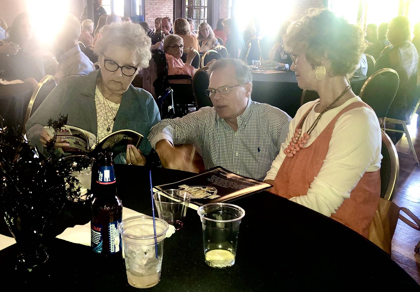 Mary Ellen Giovanine looks over the magazine profile of her late husband, Chips, along with her son, Grey, and daughter, Jill, during Thursday's NewsTribune's Illinois Valley Sports Hall of Fame banquet in LaSalle. Chips coached at Bureau Township. Buda Western and L-P high schools.