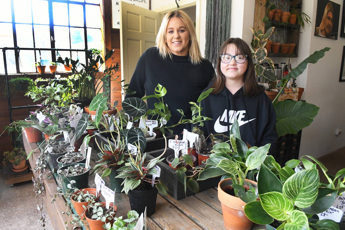 Ashley Ruch and her daughter Bostyn, 10, stand at the plant tables at their new business Grungy Roots in Grand Detour.