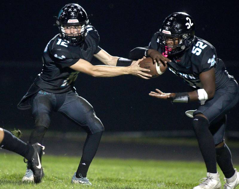 left, hands off to David Randecker against Woodstock in varsity football at Woodstock North Friday night.