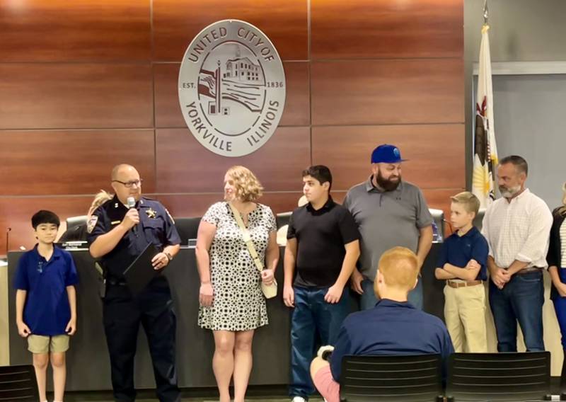 At the Yorkville City Council Aug. 27 meeting, Yorkville Deputy Chief Ray Mikolasek awards 12-year olds Daniel Torres (fourth from left) and Gavin Faitz (second from right) Valor and Lifesaving Awards for rescuing 12-year old Kaden Luangvila (first on left) from a near-drowning incident at a July pool party.