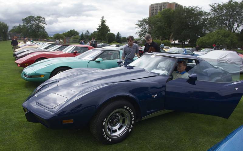 Mike West shows the ins and outs to his 1977 Chevy Coup Corvette to bidders Rich Kasiurak and Rob Kasiurak during  Bloomington Gold's Corvette Show at Pheasant Run Thursday afternoon.