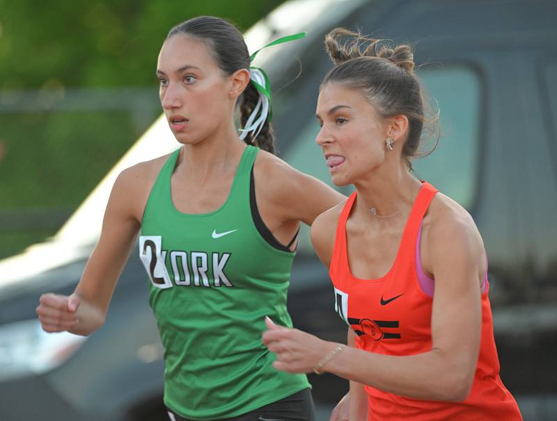 Wheaton Warrenville South’s Jenna Bachara bites her tongue as she runs with York’s Sophia Galliano-Sanchez at the start of the 800-meter run at the Lake Park Class 3A girls track and field sectional meet on Friday, May 10, 2024.