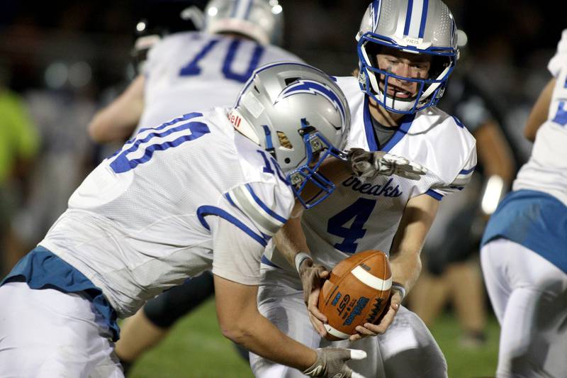 Woodstock’s Caden Thompson, right, hands off to Landen Stoltz in varsity football at Woodstock North Friday night.