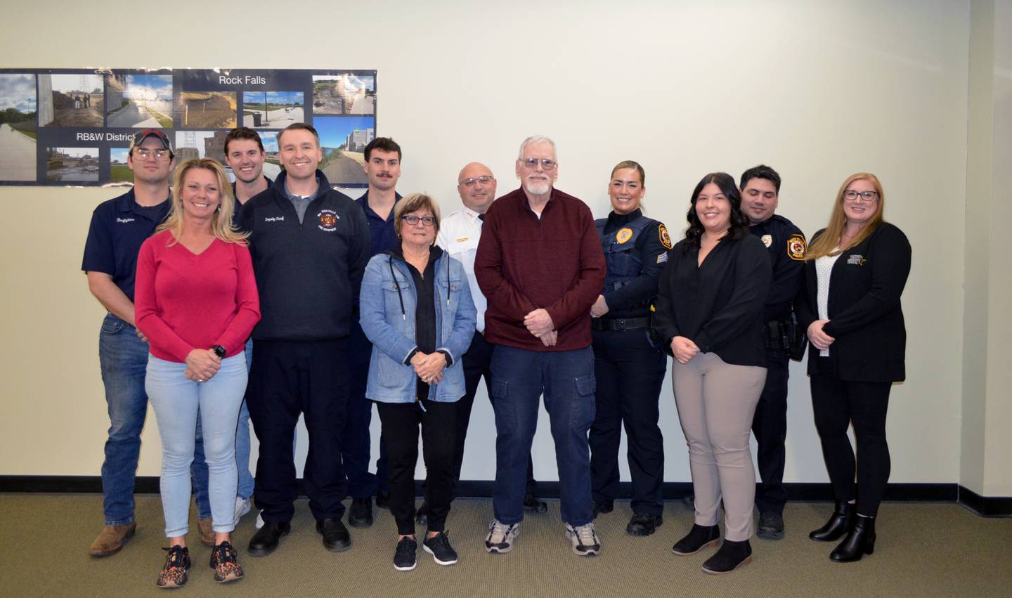 Tim Isaac, of Rockford, center, stands with his wife and daughter on March 19, 2024, surrounded by the first responders who helped save his life when he suffered cardiac arrest on Feb. 14 while driving near Interstate 88 and Illinois Route 40. In the front row, left to right, are: Angel Gaudry, Isaac's daughter; Rock Falls Deputy Fire Chief Kyle Sommers; Linda Isaac, Tim Isaac's wife; Isaac; and 911 dispatchers Alexis Echebarria and Tara Baumgartner. In the back row, left to right, are: firefighters Mark McPhillips, Matt Oswalt and Cameron Gonzalez; Rock Falls Police Chief David Pilgrim; police Sgt. Betony Gluff; and police Officer Kristofer Perez. Not pictured is CGH EMS Danny Surdez.