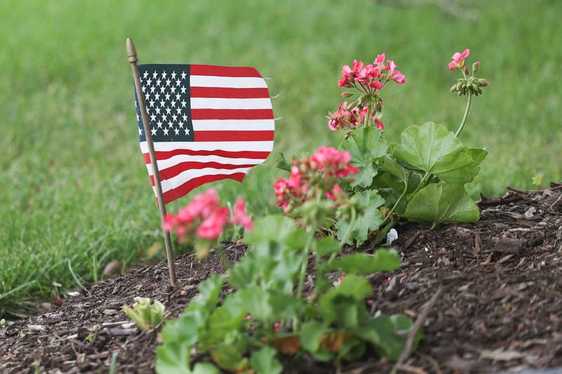 An American flag sits in a garden in front of a home along the parade route at Plainfield’s Memorial Day and Ceremony event on Monday, May 27, 2024.
