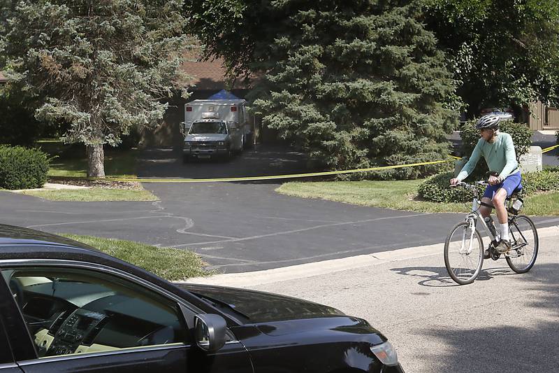 A bicyclist rides past a home in 5800 block of Wild Plum Road in unincorporated Crystal Lake on Thursday, Aug. 10, 2023, where four family members, including three females and a male “aggressor,” were killed Wednesday, as the McHenry County Sheriff Department  continue to investigate the scene