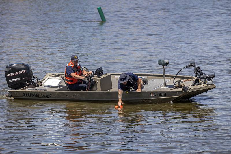 A firefighter picks up a marker Thursday, May 23, 2024 just off the Peoria Avenue bridge.