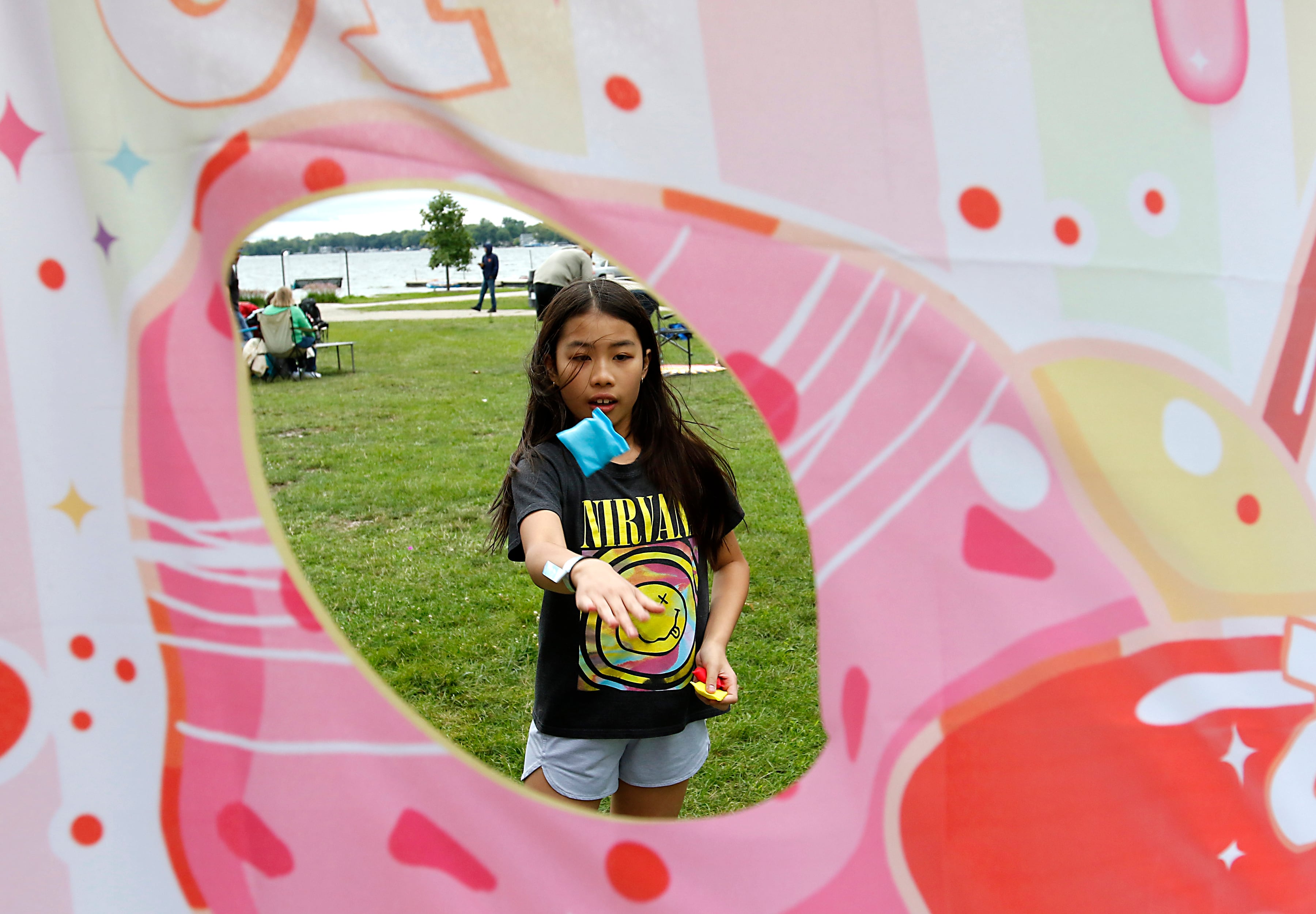 Harper Nguyen, 9, tosses a bag into the Warps Corps bag toss game during the Ice Cream Fest on Friday, Aug. 9, 2024, at Crystal Lake’s Main Beach.  The second annual event featured music, ice cream venders and an ice cream eating contest.