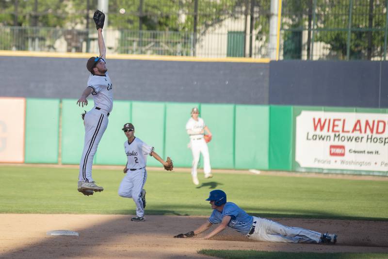 Joliet Catholic’s Aidan Voss leaps for the ball ahead of the sliding Jack Steckler of Columbia Friday, June 3, 2022 during the IHSA Class 2A baseball state semifinal.