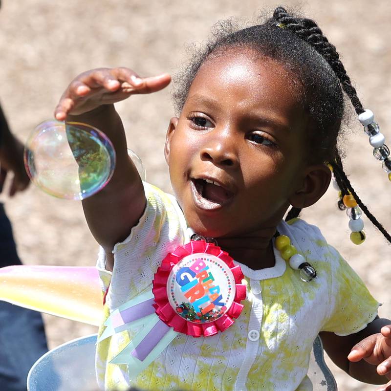 Jahnora Sturges, 3, from DeKalb tries to catch a bubble during Camp Power at Welsh Park in DeKalb. Camp Power, which is run by the Kishwaukee Valley YMCA, is a summer program for youth at University Village that provides positive activities for kids.