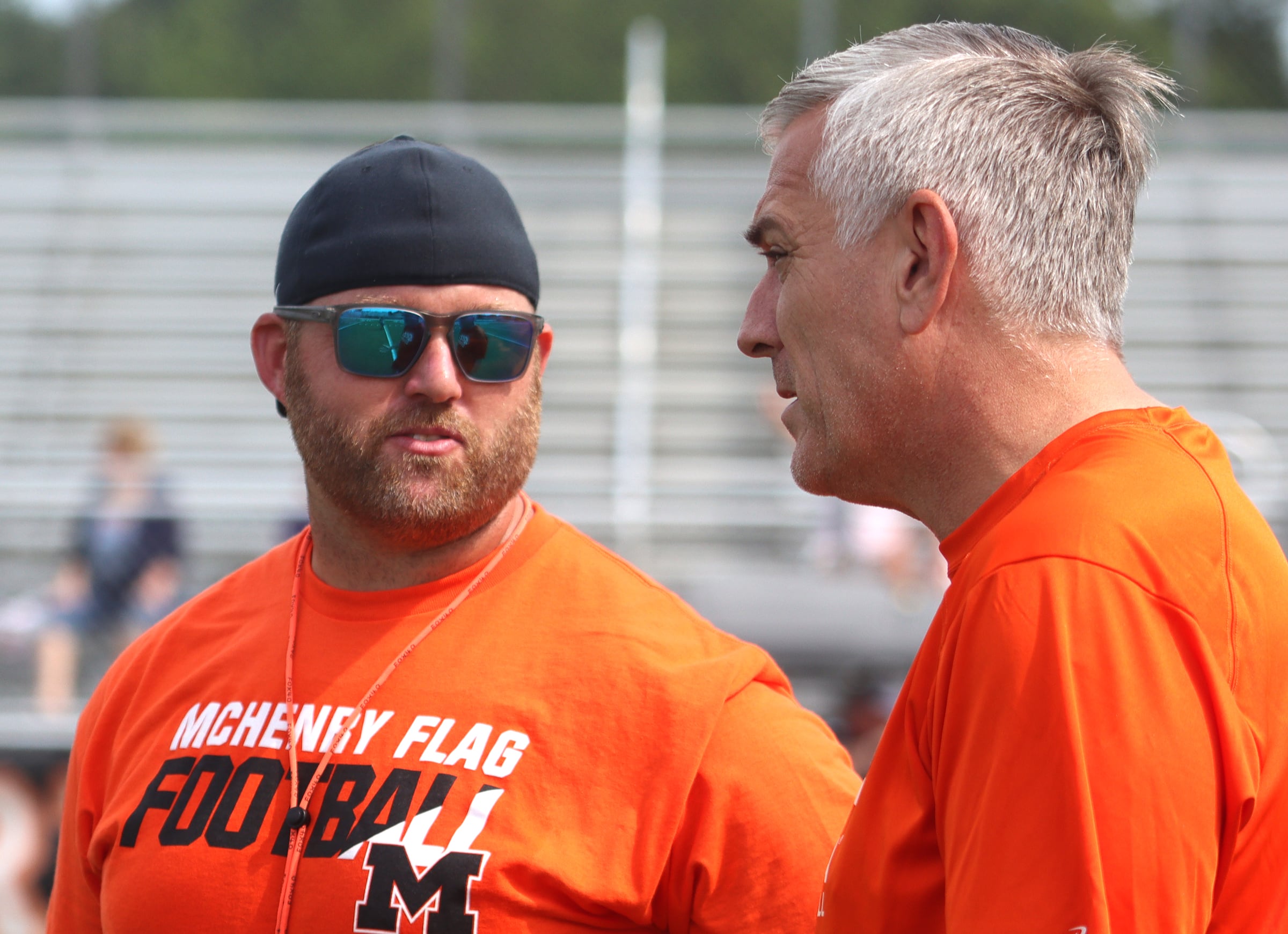 McHenry flag football Head Coach Dennis Hutchinson, left, speaks with former bears player Jim Schwantz as the Chicago Bears and McHenry Community High School hosted a flag football clinic at McCracken Field Wednesday, July 31, 2024.