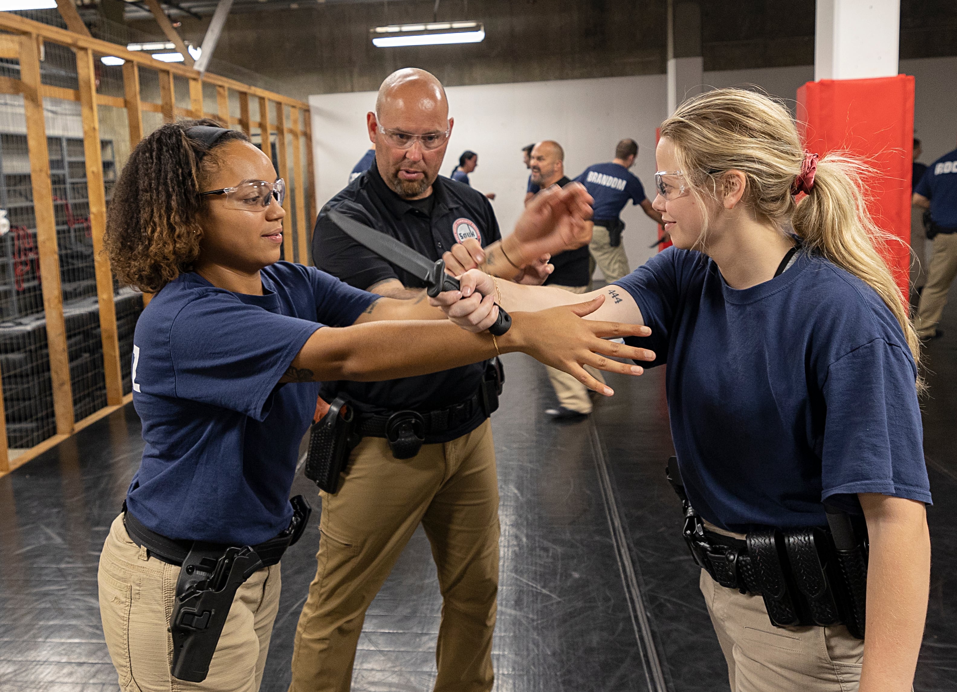 John Atkins instructs recruits Marielys Sanchez (left) and Paige Talty on knife defense Wednesday, July 17, 2024, at the Sauk Valle Police Academy.