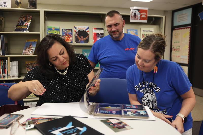 Judith Nash, left, looks over photos with her former students Evan Giardina and Amanda Tancl at Hufford Junior High School on Friday, August 23, 2024 in Joliet. 31 years later, all three work for District 86.