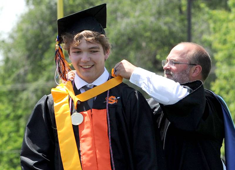 Valedictorian William Lappe receives a medal for Principal Shane Darnell during Sandwich High School's graduation ceremony on the football field, Sunday, May 19, 2024.