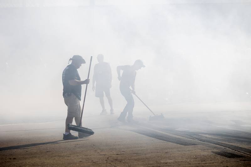 The clean-up crew brooms off bits of rubber torn off the tires from the burn-out competition Monday, June 10, 2024, in Rock Falls.