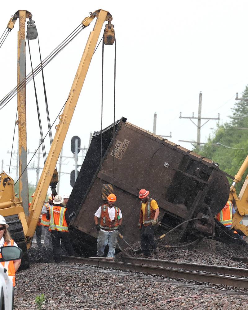 Cranes are attached to a tipped over coal car after a BNSF Railway train traveling east derailed Wednesday, July 10, 2024, near Route 34 on the west side of Somonauk.