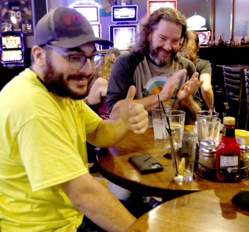 Justin Triplett, (right) Joshua Zapata, and James Lamping, from the Phoenix, a recovery nonprofit, celebrate answering a trivia question correctly on Tuesday, Oct. 8, 2024, during a trivia night at Galati's Hideaway Restaurant in Cary. The recovery nonprofit takes people in recovery on outings such as hiking, bike riding, rock wall climbing, and trivia nights.